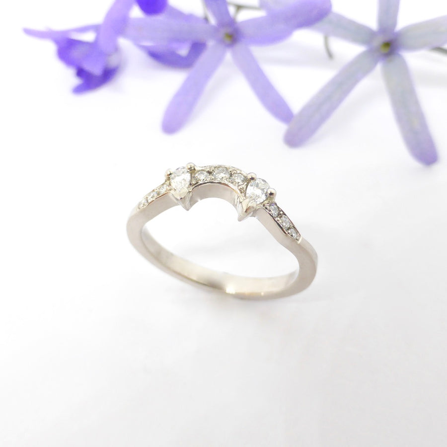 Engagement ring with a pear shaped sapphire and kite shaped diamonds set into white gold, matched with a fitted custom made pear and round diamond wedding ring by Louise Shaw Jewellery