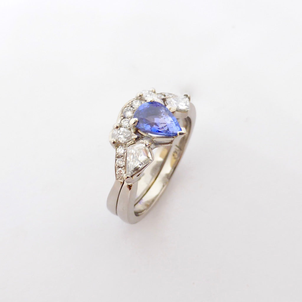 Engagement ring with a pear shaped sapphire and kite shaped diamonds set into white gold, matched with a fitted custom made pear and round diamond wedding ring by Louise Shaw Jewellery